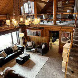 Large open-concept lodge interior with high ceilings, chandelier lighting, sofas, and loft seating in Fairbanks, Alaska