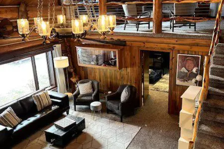 Large open-concept lodge interior with high ceilings, chandelier lighting, sofas, and loft seating in Fairbanks, Alaska