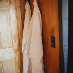 Two white robes hanging on a wooden wall inside a Fairbanks Alaska treehouse rental