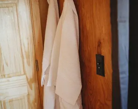 Two white robes hanging on a wooden wall inside a Fairbanks Alaska treehouse rental