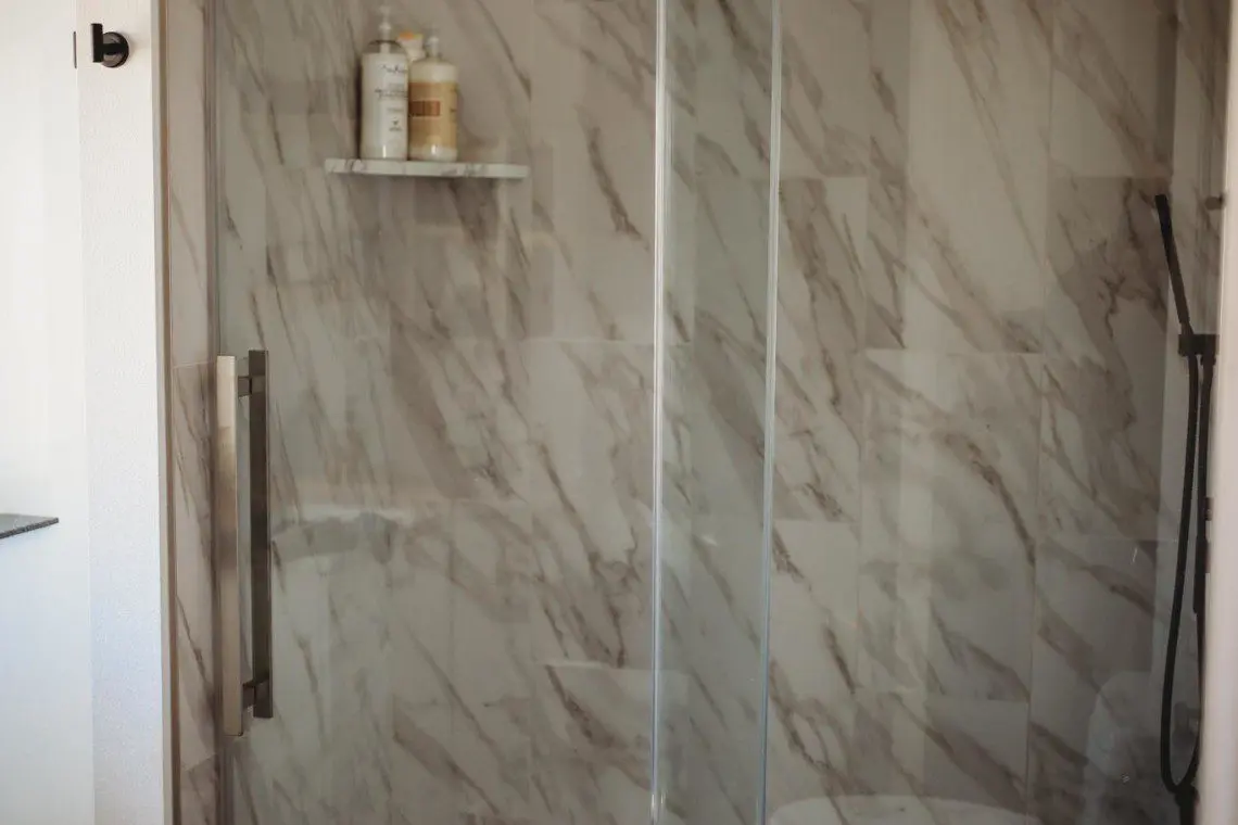 Glass-enclosed shower with marble-style tile in a modern Fairbanks treehouse bathroom