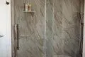 Glass-enclosed shower with marble-style tile in a modern Fairbanks treehouse bathroom