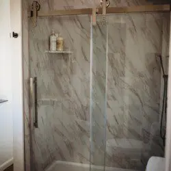 Glass-enclosed shower with marble-style tile in a modern Fairbanks treehouse bathroom