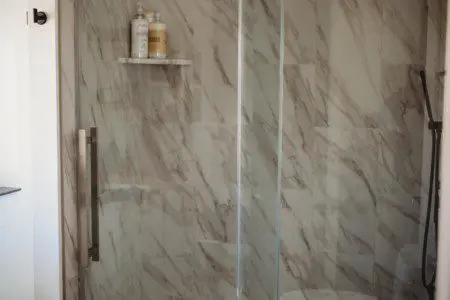 Glass-enclosed shower with marble-style tile in a modern Fairbanks treehouse bathroom