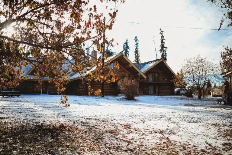 Log cabin lodge in Fairbanks Alaska with light snow and autumn trees