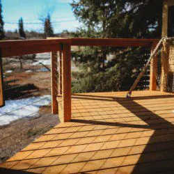 Wooden treehouse cabin with rope bridge entrance nestled in pine forest near Fairbanks, Alaska