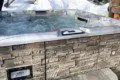 Stone-lined outdoor hot tub with bubbling water set in snowy landscape at Alaska adventure lodge near Fairbanks