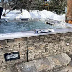 Stone-lined outdoor hot tub with bubbling water set in snowy landscape at Alaska adventure lodge near Fairbanks