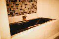 Black soaking bathtub with tiled backsplash in a Fairbanks Alaska treehouse bathroom
