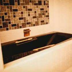 Black soaking bathtub with tiled backsplash in a Fairbanks Alaska treehouse bathroom