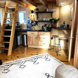 Inviting Fairbanks treehouse interior with hammock, teal sofa, cozy rug, and natural wood decor