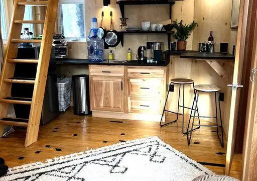 Inviting Fairbanks treehouse interior with hammock, teal sofa, cozy rug, and natural wood decor