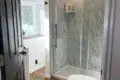Bright bathroom with glass shower, wood floors, and white walls in a Fairbanks treehouse rental