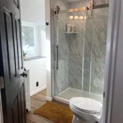 Bright bathroom with glass shower, wood floors, and white walls in a Fairbanks treehouse rental