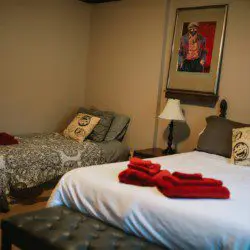 Cozy Fairbanks lodge bedroom with two beds, red towels, pillows, and warm lighting—ideal for wedding or adventure stays