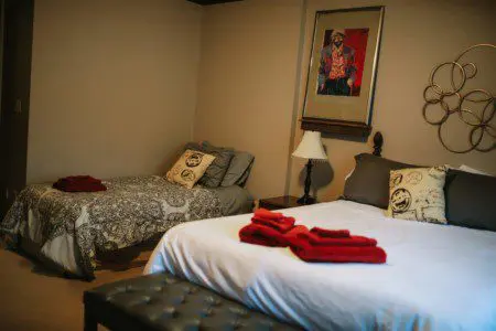 Cozy Fairbanks lodge bedroom with two beds, red towels, pillows, and warm lighting—ideal for wedding or adventure stays