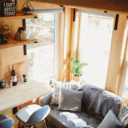 Cozy living area with sofa, bar stools, and large windows inside a Fairbanks Alaska treehouse