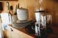Close-up of plates, bowls, mugs, and glasses on a wooden shelf in a Fairbanks Alaska treehouse
