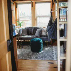Cozy treehouse living room with couch, pouf, hammock chair, and large windows in Fairbanks Alaska