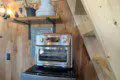 Small oven on mini fridge with wooden stairs and shelving in a rustic Fairbanks Alaska treehouse
