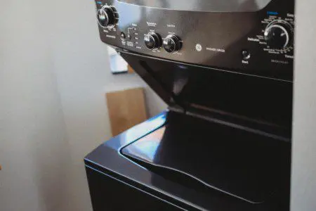 Black stacked washer and dryer unit inside a Fairbanks Alaska lodge, offering convenience for long stays