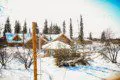 Rustic log lodge surrounded by light snow and trees in Fairbanks, Alaska on a bright day