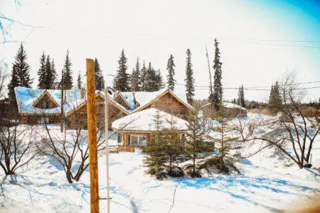 Rustic log lodge surrounded by light snow and trees in Fairbanks, Alaska on a bright day