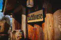 Wooden bathhouse sign mounted on log wall at Fairbanks Alaska lodge with carved bear sculpture