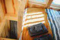 Sunlit wooden bed with folded towels and blankets in a Fairbanks Alaska treehouse rental