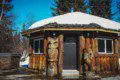Round log cabin bathhouse with owl and bear wood carvings in snowy Fairbanks Alaska setting