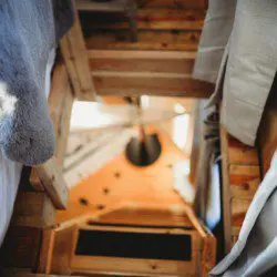 Wooden ladder leading to loft beside windows and kitchenette in Fairbanks Alaska treehouse