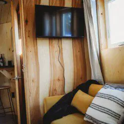 Interior view of treehouse rental in Fairbanks Alaska with wooden walls, TV, and yellow couch
