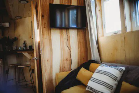 Interior view of treehouse rental in Fairbanks Alaska with wooden walls, TV, and yellow couch