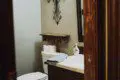Cozy bathroom with wooden vanity, wall cross decor, and toilet in a Fairbanks Alaska lodge or treehouse rental