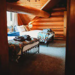 Neatly folded gray towels on a white bed with striped pillow in a bright Fairbanks Alaska treehouse rental bedroom
