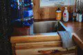 Compact wooden sink station with water jug and supplies in a Fairbanks Alaska treehouse rental