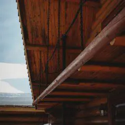Exterior view of Fairbanks treehouse with log walls, covered porch, and spiral staircase in snowy setting