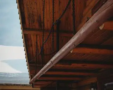 Exterior view of Fairbanks treehouse with log walls, covered porch, and spiral staircase in snowy setting