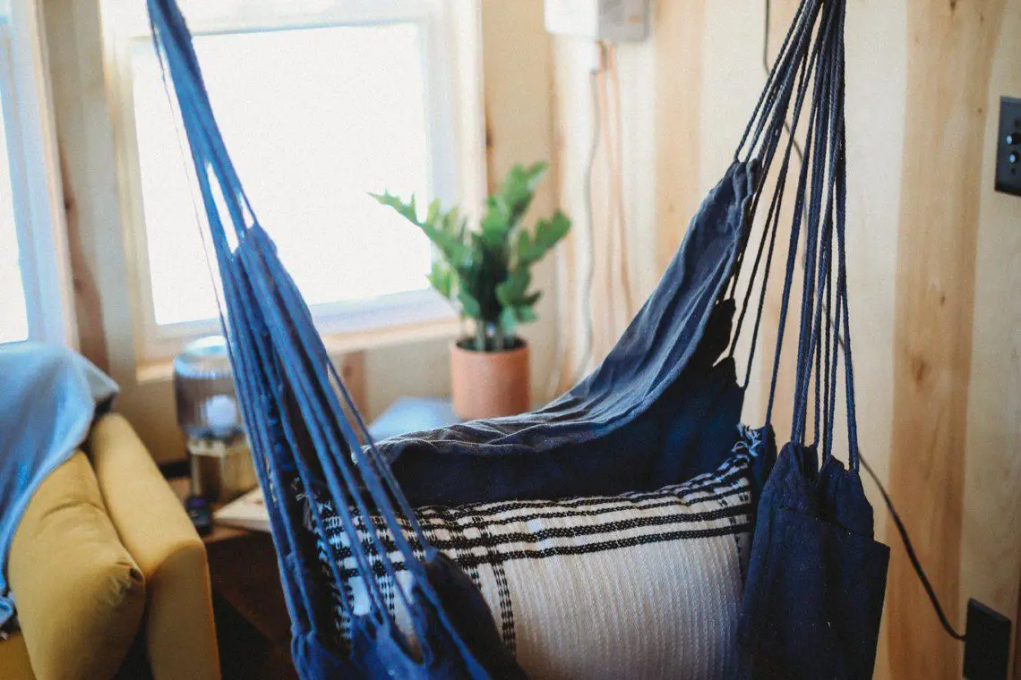 Blue hanging hammock chair by a window in a cozy Fairbanks Alaska treehouse rental