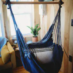Blue hanging hammock chair by a window in a cozy Fairbanks Alaska treehouse rental