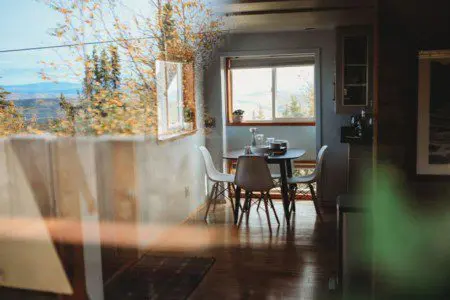 Reflection of dining area and autumn trees seen through a window in a Fairbanks Alaska treehouse