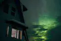 Northern lights glowing above a Fairbanks treehouse-style lodge at night