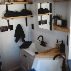 Compact modern bathroom with dual sinks, wood shelves, and black fixtures in Fairbanks Alaska rental