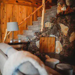 Cozy interior with stone accent wall, carpeted stairs, and log railing in a Fairbanks Alaska treehouse rental