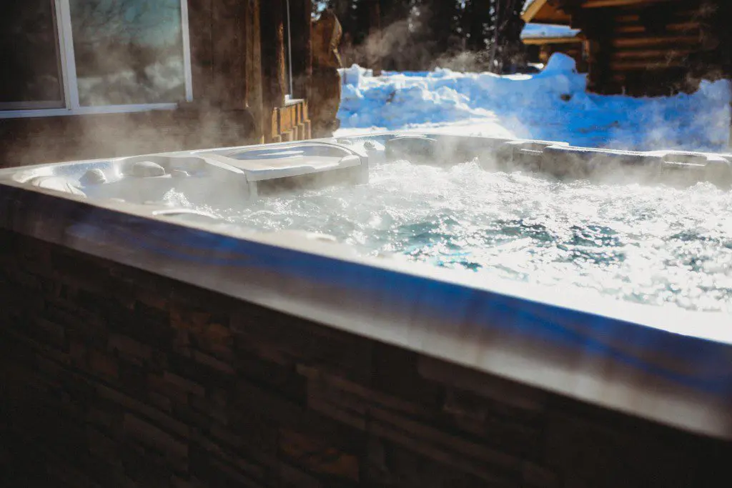 Steam rising from bubbling hot tub beside rustic cabin in snowy Fairbanks Alaska setting