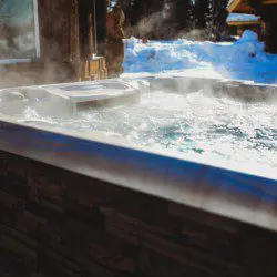 Steam rising from bubbling hot tub beside rustic cabin in snowy Fairbanks Alaska setting