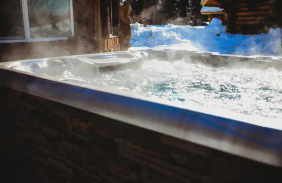 Steam rising from bubbling hot tub beside rustic cabin in snowy Fairbanks Alaska setting