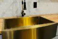 Shiny gold farmhouse kitchen sink with modern faucet in a Fairbanks Alaska treehouse rental
