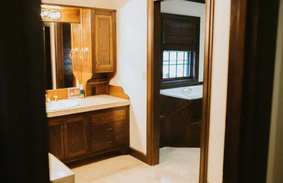 Traditional bathroom with wood cabinetry and connected tub room in a Fairbanks Alaska lodge or treehouse rental