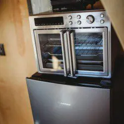 Close-up of a mini fridge and stainless steel countertop oven in a wood-paneled Fairbanks Alaska treehouse